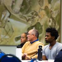 room full of people listening, a student in a gray T-shirt is in focus
